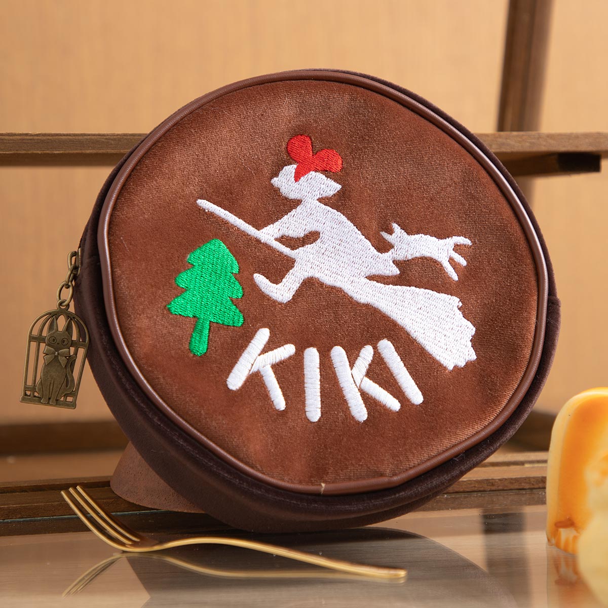 Round velour Kiki's Delivery Service pouch with embroidered Kiki and Jiji flying past a tree
