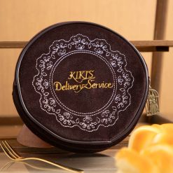 Reverse of the Kiki's Delivery Service pouch with gold script and embroidered cake doily
