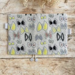 butterfly pattern in vibrant yellow, plus greys and browns, and a pale grey vegan 'leather' trim.