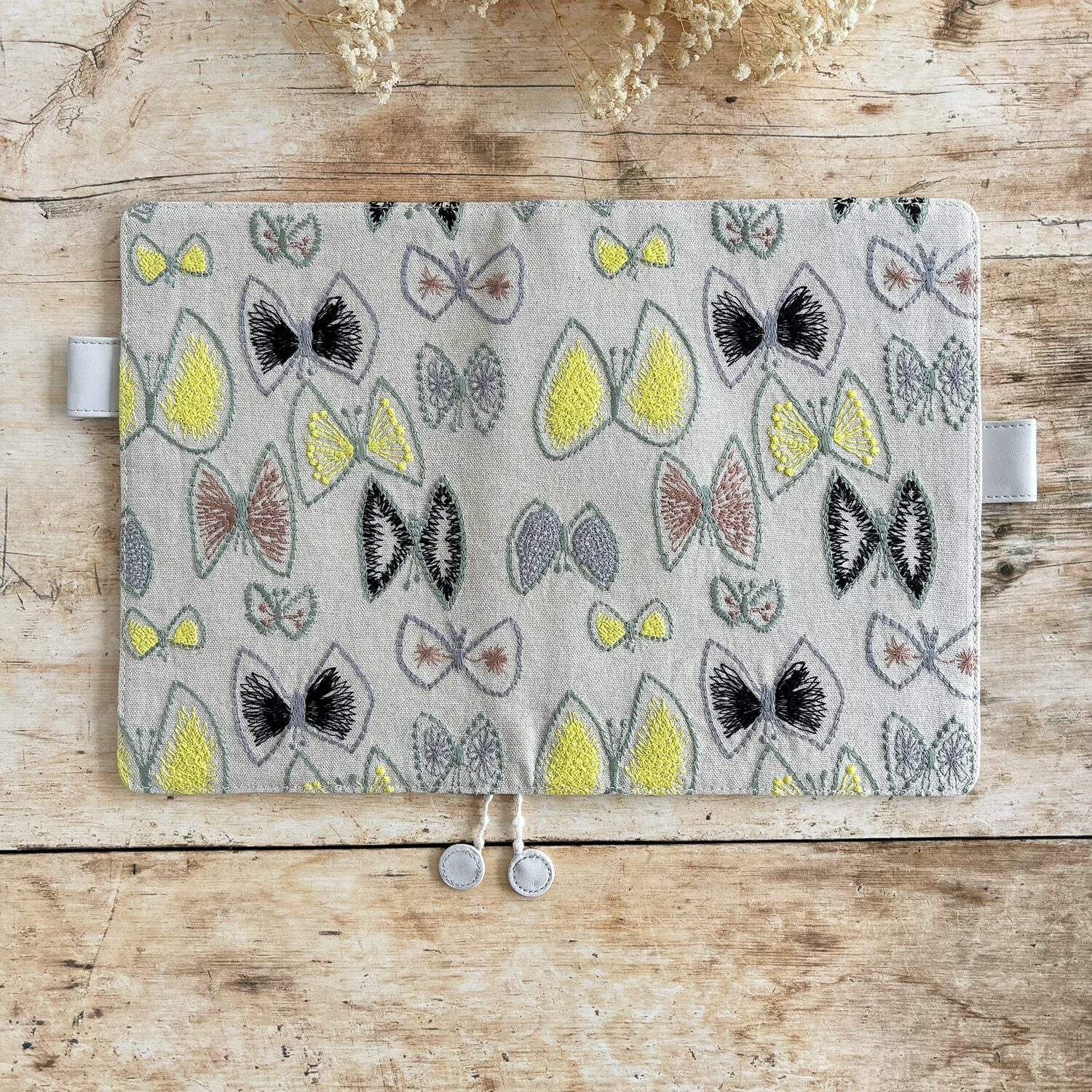 butterfly pattern in vibrant yellow, plus greys and browns, and a pale grey vegan 'leather' trim.