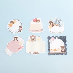 Bear-themed sticker flakes arranged on a pale blue background, featuring cakes, sweets, plates, and a teddy bear café party scene by Nakauchiwaka for Papier Platz.