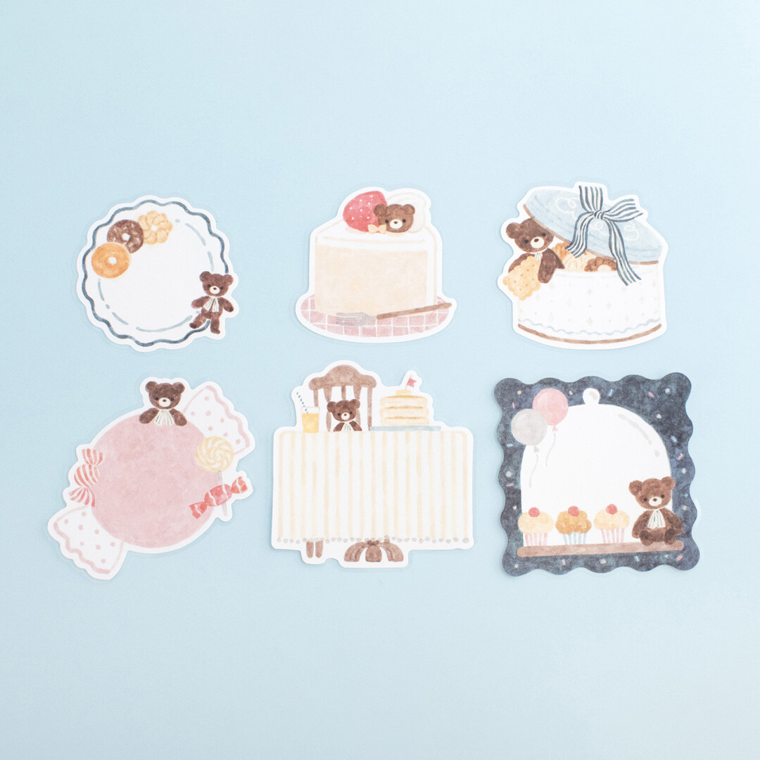 Bear-themed sticker flakes arranged on a pale blue background, featuring cakes, sweets, plates, and a teddy bear café party scene by Nakauchiwaka for Papier Platz.