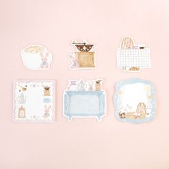 Individual Papier Platz Rabbit’s Café stickers laid out on a pink background, showing rabbits enjoying café scenes with coffee grinders, tables, notebooks, kitchen counters, and cosy interior details.