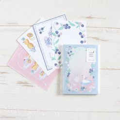 Papier Platz Otegaru Swan memo pad in clear packaging, shown alongside matching loose memo sheets on a white wooden background.