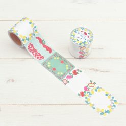 Papier Platz PuPuPu sticky roll with fruit wreath and pastry-themed labels, roll extended and product jar shown on wooden surface.