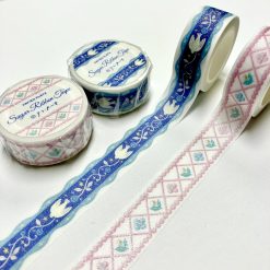 Papier Platz die-cut washi tape unrolled on a white background, featuring a scalloped ribbon-style edge with white tulips, stars, and floral motifs on a deep blue design.