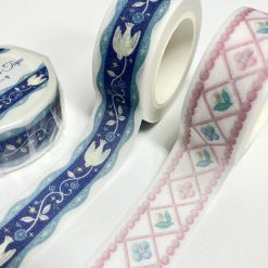 Papier Platz die-cut washi tape unrolled on a white background, showing a pink ribbon-style lattice pattern with small floral details and scalloped edges, alongside the rolled tape.