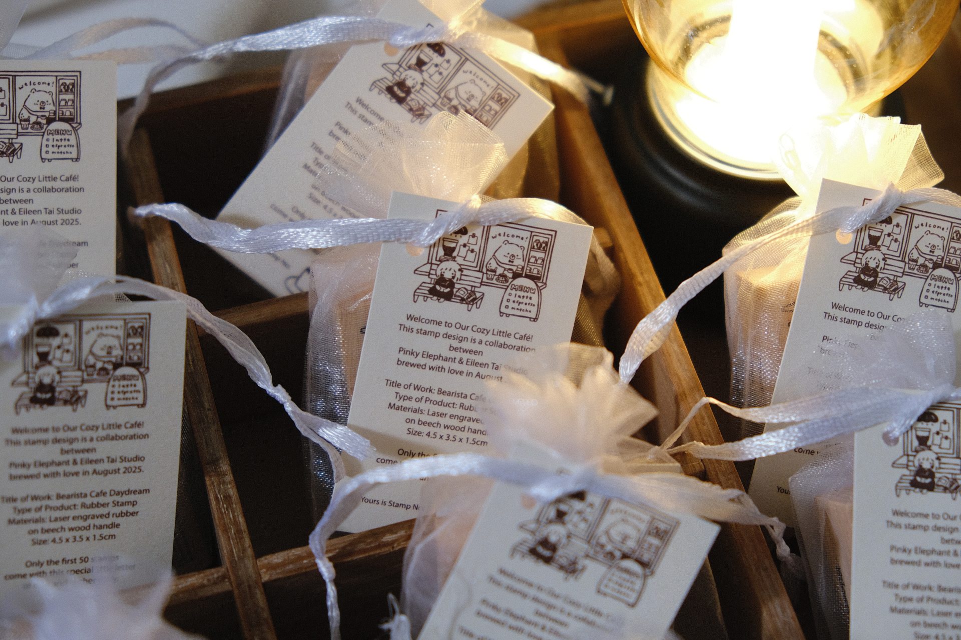 Close-up styled photo of Eileen Tai “Bearista Café Daydream” rubber stamp packaging in organza bags in a wooden tray.