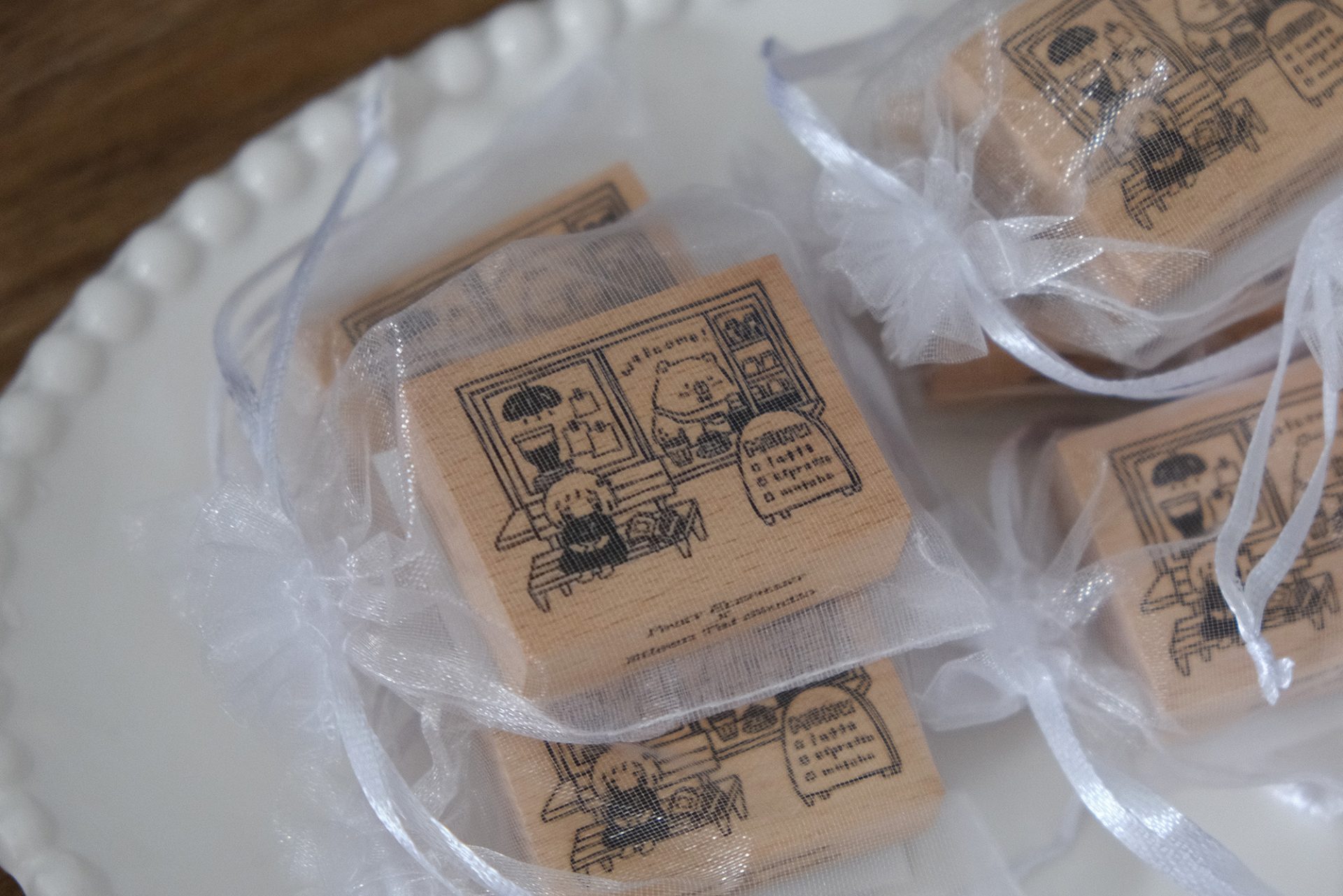 Styled photo of Eileen Tai “Bearista Café Daydream” rubber stamps packaged in organza bags in a wooden tray beside a glowing lamp.
