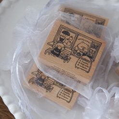 Styled photo of multiple Eileen Tai “Bearista Café Daydream” rubber stamps packaged in organza bags arranged on a plate.