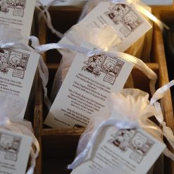 Angled styled photo of an Eileen Tai “Bearista Café Daydream” rubber stamp in an organza bag on a white plate.