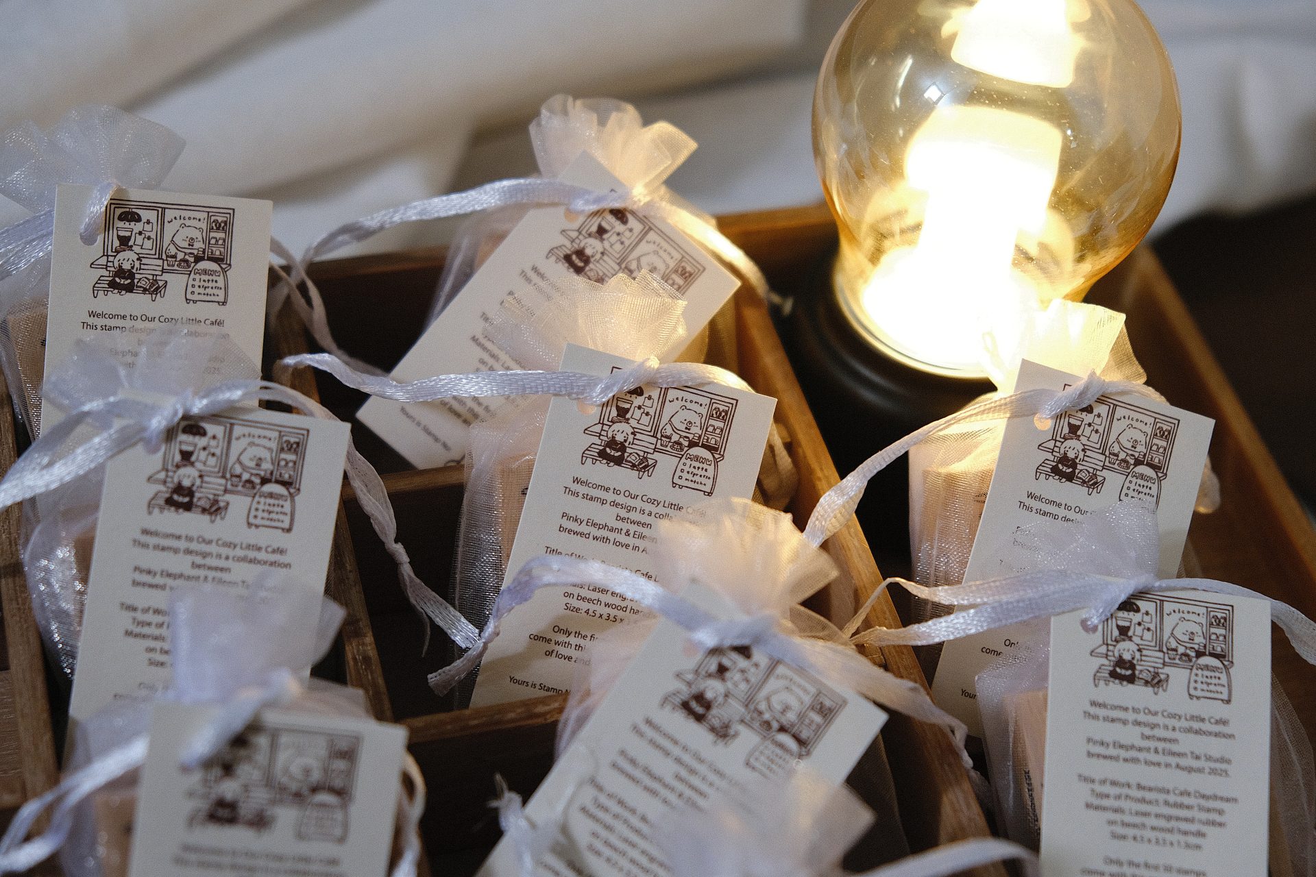 Styled photo of a single Eileen Tai “Bearista Café Daydream” rubber stamp inside an organza bag on a white plate.