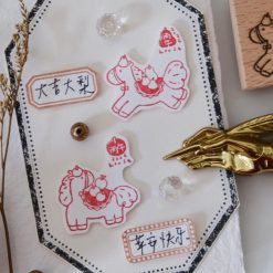 Flat lay of Eileen Tai Year of the Horse wooden rubber stamp with stamped horse illustrations and decorative stationery accessories.