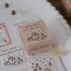 Let’s Play wooden stamp showing a child playing in the rain with the phrase “let’s play even when it rains”.