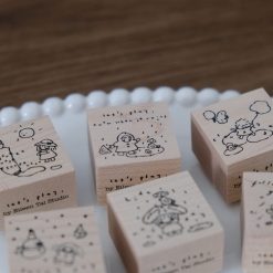 Close-up of a rainy day wooden stamp featuring a child playing in the rain.