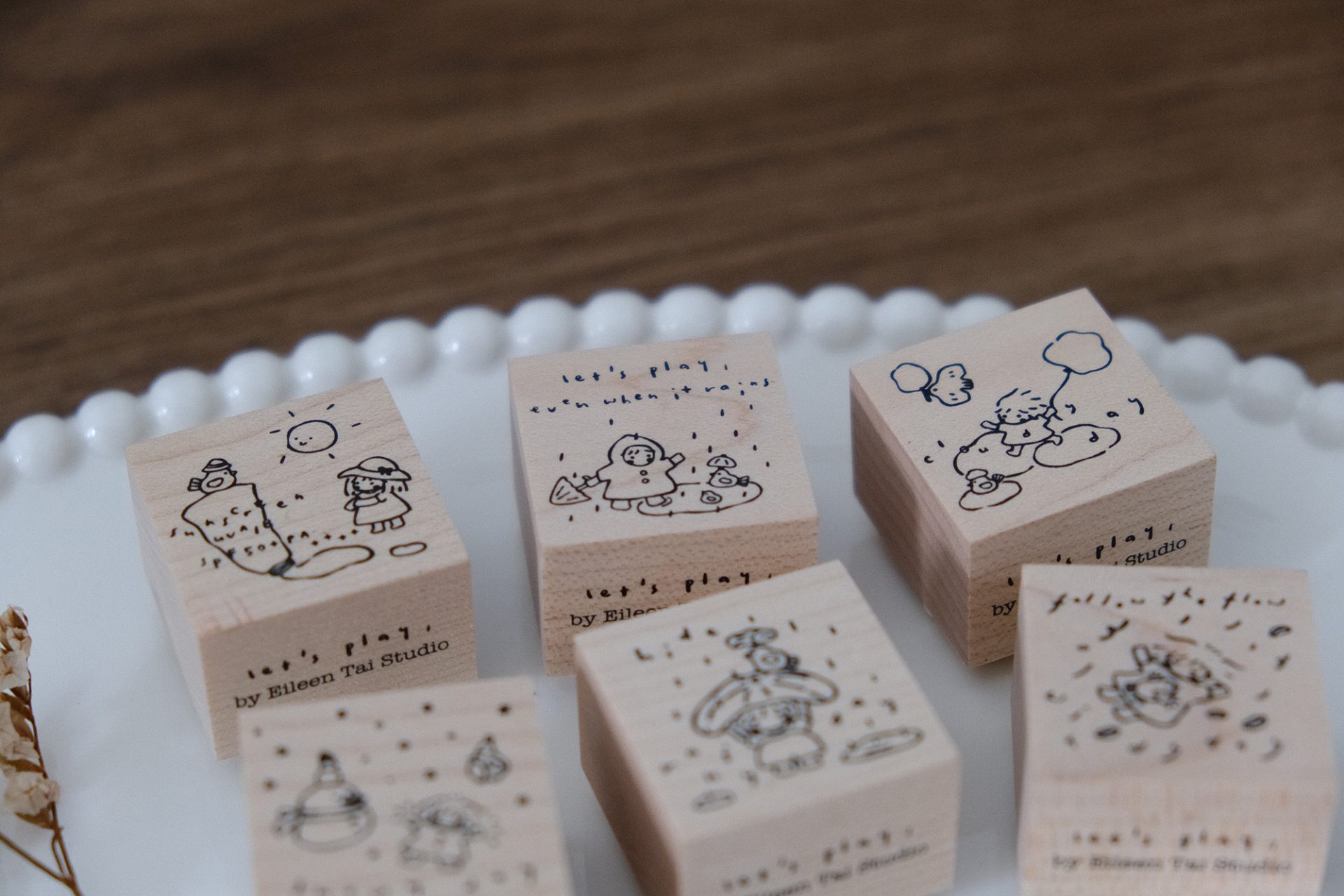 Close-up of a rainy day wooden stamp featuring a child playing in the rain.