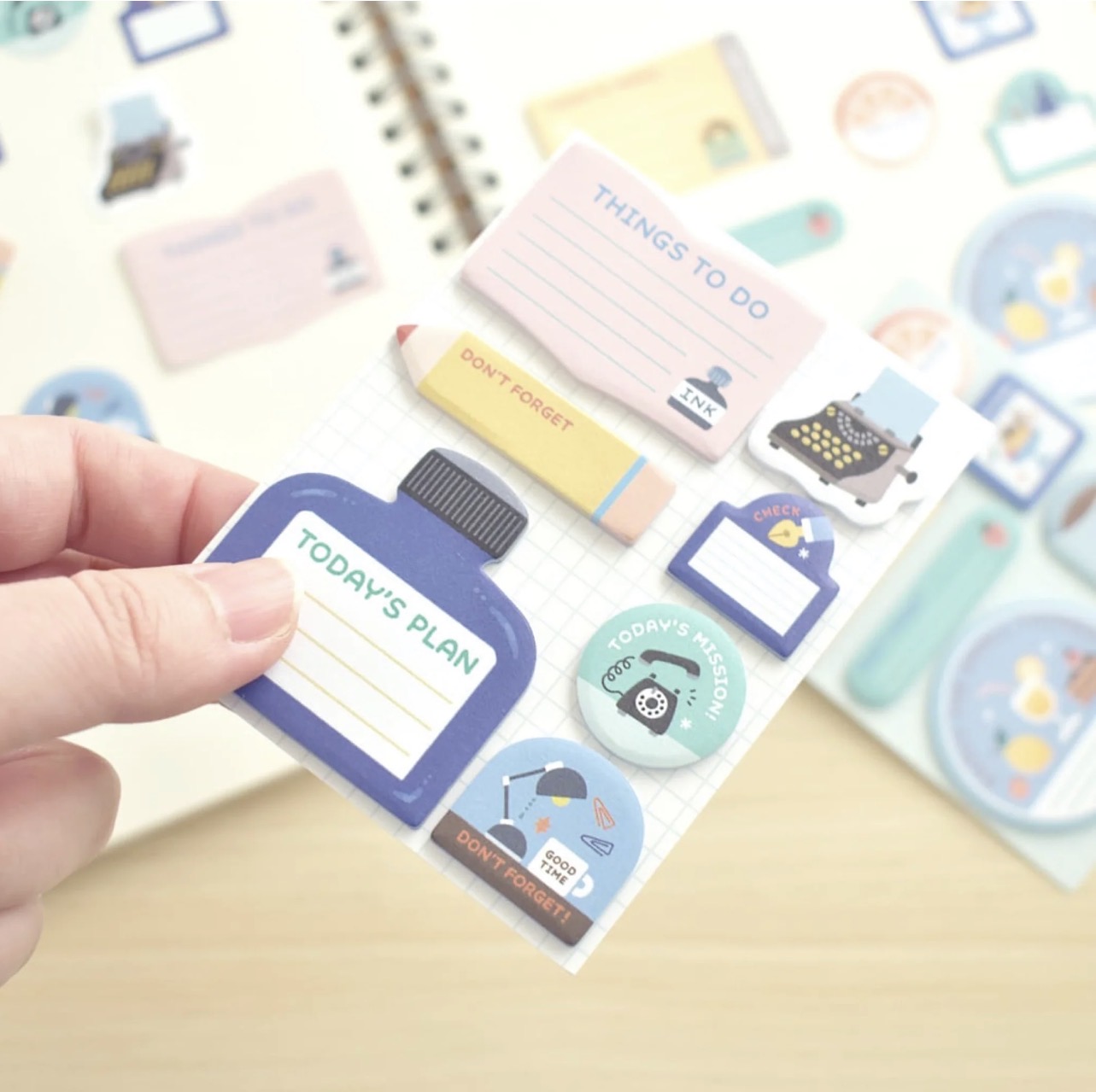 Papier Platz mini sticky notes by Eric Small Things shown in blue-themed packaging with stationery illustrations, photographed on a light wood surface.